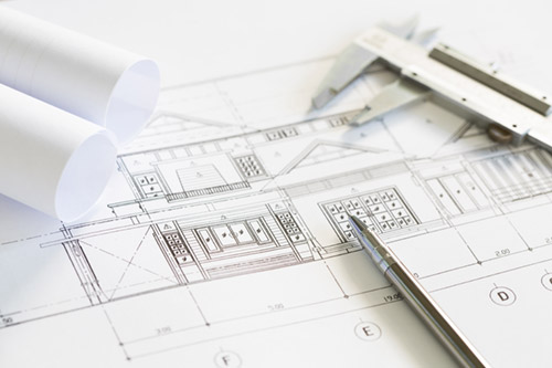Architectural blueprints with caliper and pen used for construction design and planning.