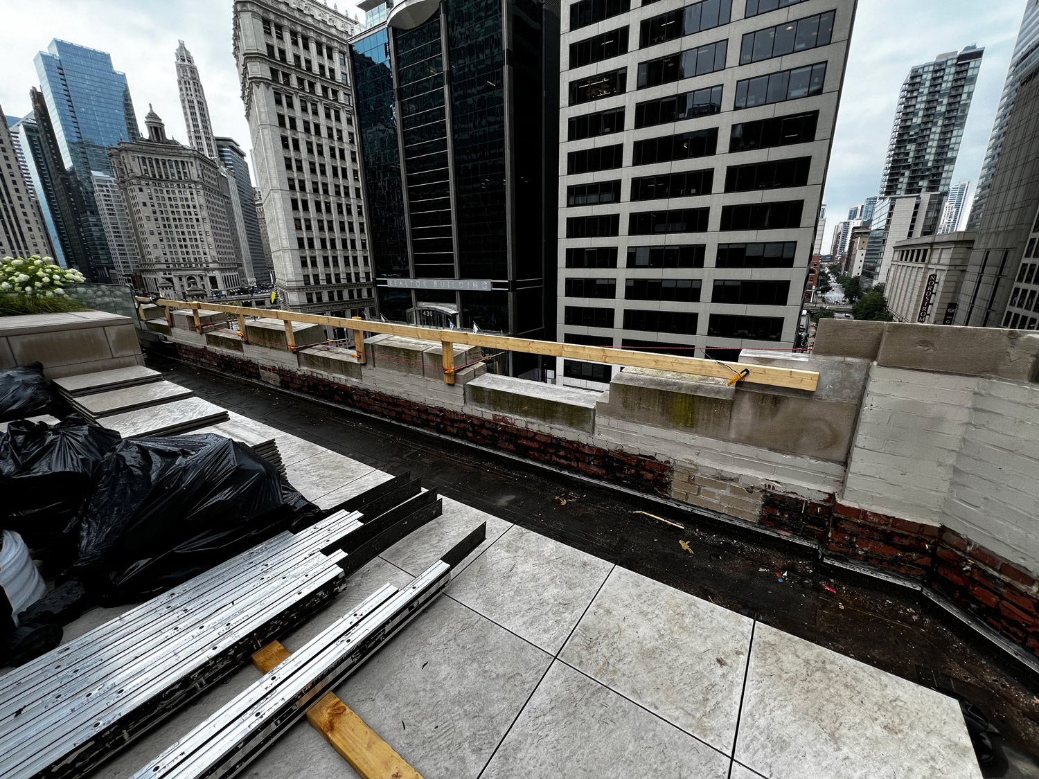 Chicago rooftop construction restoration project with masonry repair and protective railing overlooking downtown buildings